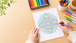 曼荼羅塗り絵の初心者向けの始め方という記事に掲載する画像です。 曼荼羅塗り絵を描いている手元の画像を作ってほしいです。 机には色鉛筆のほか、カラーペンも並べてください